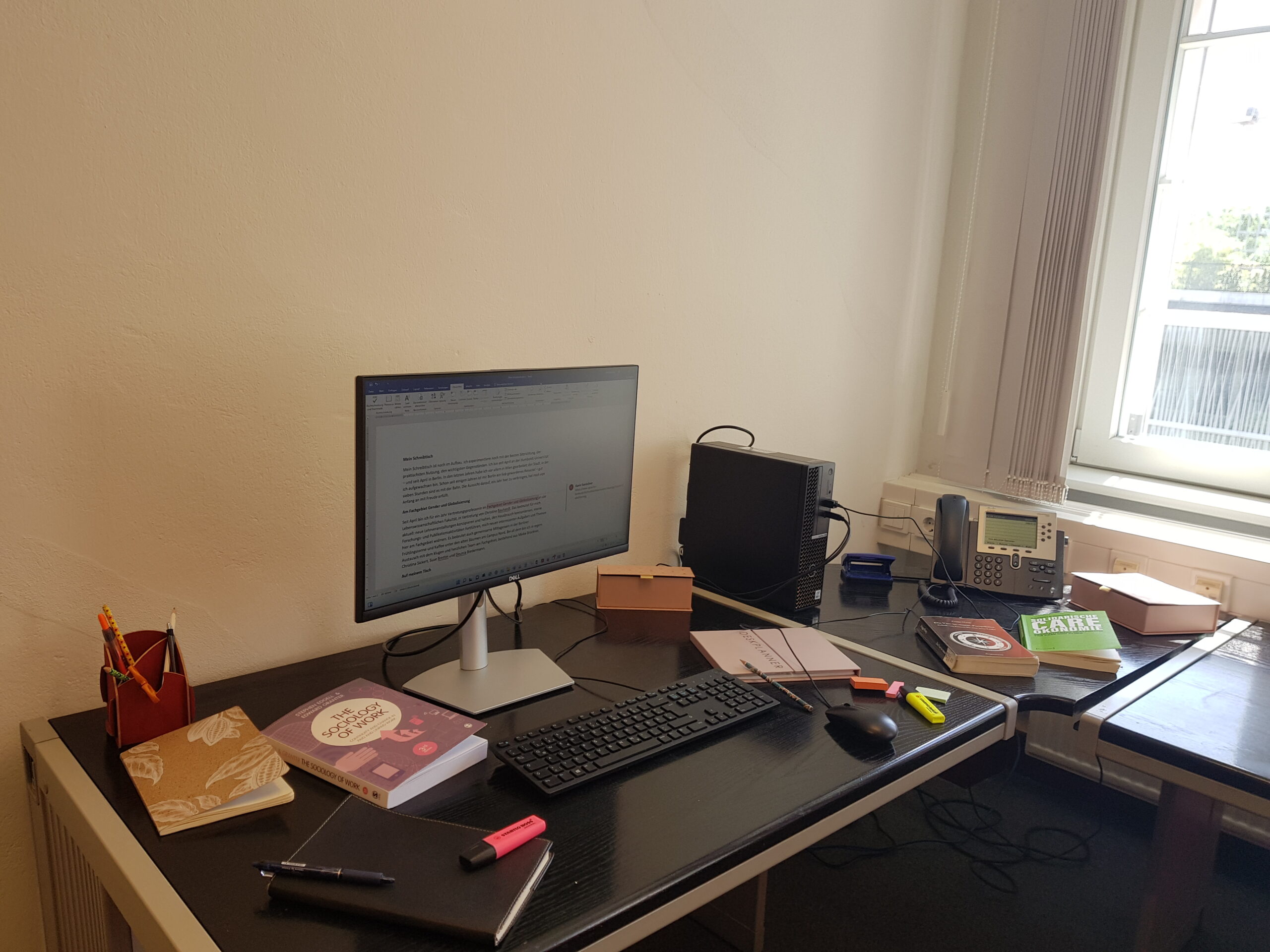 Das Bild zeigt den Schreibtisch der Autorin, auf dem unterschiedliche Utensilien wie Bücher und Unterichtsmaterial liegen und ein Computer steht.