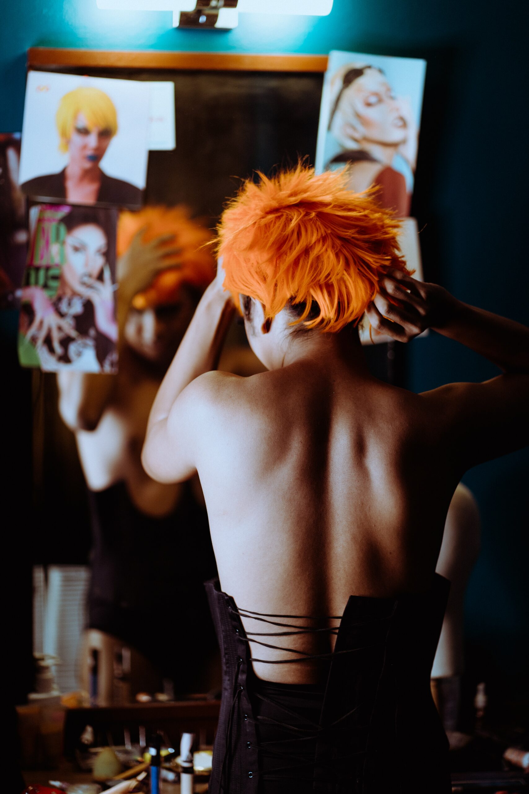 the image shows a person adjusting an orange wig on their head in front of a mirror.